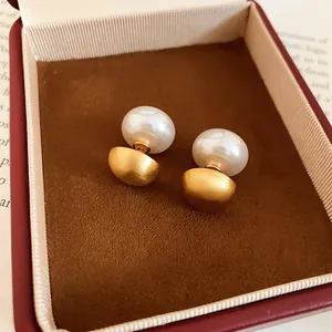 Detailed view of matte gold and white pearl double-sided stud earrings in a jewelry gift box