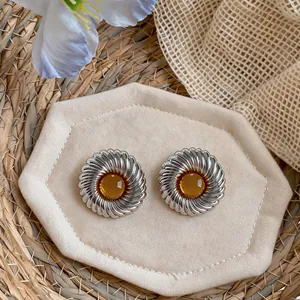 Detailaufnahme von Vintage-Ohrsteckern in Silberoptik mit bernsteinfarbenem Harz.