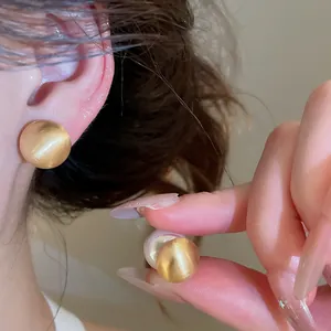 Detail close-up view showing the brushed gold finish and pearl stud earring worn on ear