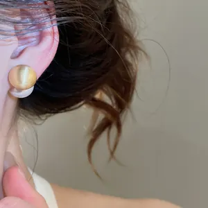 Detailed close-up showing elegant brushed metal and pearl earrings worn on a model's ear