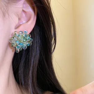 Close-up detail of deep sea blue bubble flower stud earrings with silver needles on ear