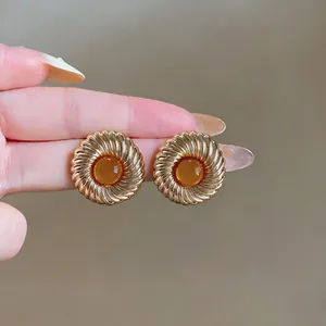 Nahaufnahme von eleganten goldfarbenen runden Ohrsteckern mit bernsteinfarbenem Harz.