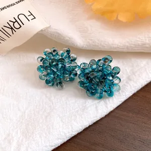 Macro detail of exquisite deep sea blue bead flower stud earrings on white fabric