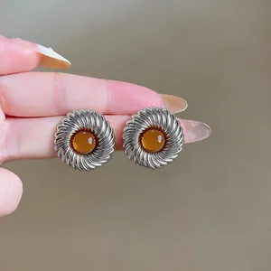Detaillierte Makroaufnahme von silbernen Vintage-Spiralohrsteckern mit bernsteinfarbenem Harz