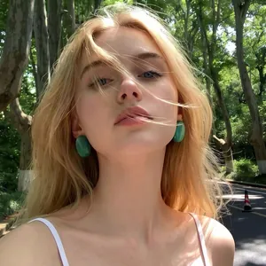 Close-up of vintage style teal oval stud earrings on blonde model in natural light