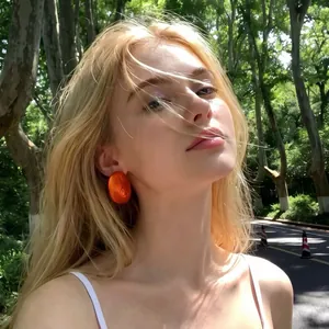 Close-up detail of vintage French style vibrant orange translucent acrylic stud earrings