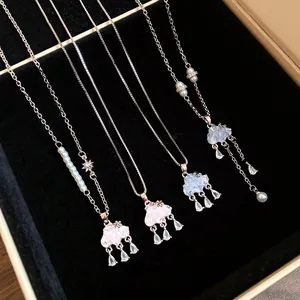 Detail of cloud necklaces with zircon water-drop tassels and pearl accents in a jewelry box