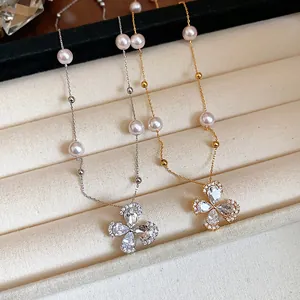 Detailed shot of two pearl necklaces with floral zircon pendants on a velvet tray.