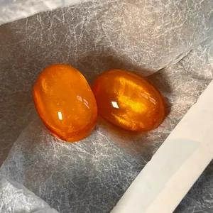Close-up of vibrant orange translucent resin stud earrings with a retro French style