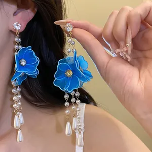 Detailed shot of long tassel earrings featuring blue silk flowers and elegant pearls