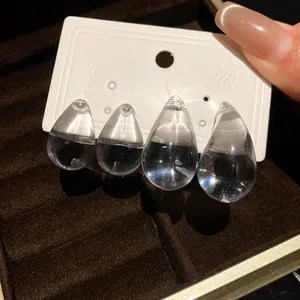Close-up detail shot of transparent acrylic teardrop earrings on a white display card.