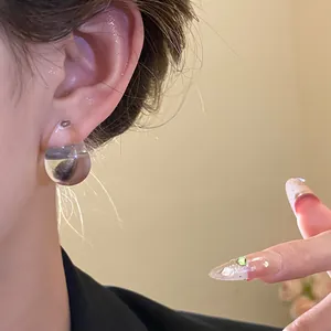 Detail shot of a minimalist transparent acrylic water drop stud earring on model's ear