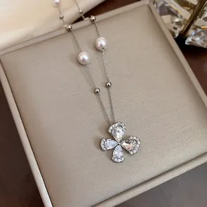 Macro detail shot of an elegant zircon flower and pearl necklace in gold plating