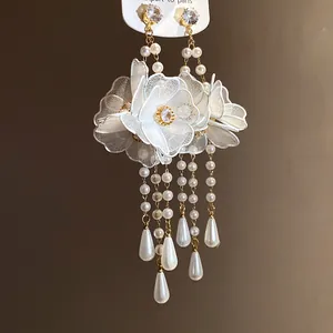 Close-up detail showing the intricate white mesh flowers and teardrop pearl tassels.