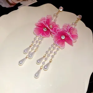 Close-up detail of pink mesh flower earrings with long pearl tassels and zircon accents