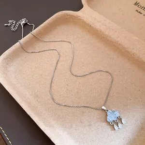 Detailed view of silver-tone necklace with blue zircon cloud pendant and water drop tassels