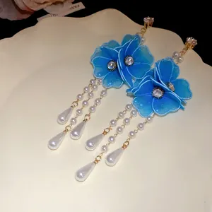 Macro shot of blue mesh flower earrings with zircon center and white pearl drops.