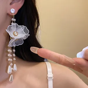 Close-up detail view of white mesh flower earrings with pearl tassels and zircon