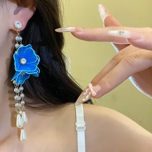 Detail view of elegant blue mesh flower earrings featuring long pearl tassels worn on ear