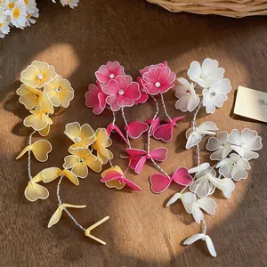 Detailed view of handmade woven flower earrings with pearls in yellow, pink and white