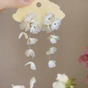 Close-up detail of handmade white mesh flower petals on long silver chain dangle earrings