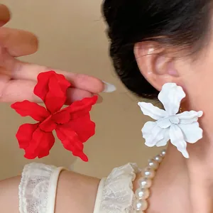 Close-up view of elegant matte spray-painted flower earrings in red and white colors
