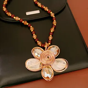 Détail macro d'un collier fleur fait main avec perles de verre colorées et fil torsadé
