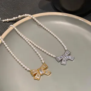 Macro detail of luxurious bow pendants encrusted with baguette stones on pearl necklaces.