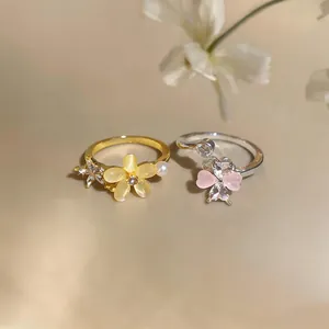Detailed view of gold and silver zircon flower rings with cat's eye and pink stones