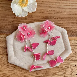 Close-up view of handmade pink floral tassel earrings with delicate mesh petals on wood background
