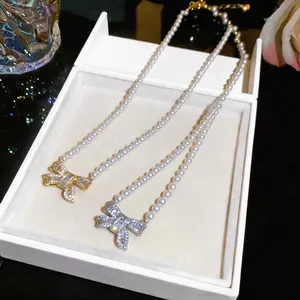 Close-up detail of 18k gold plated pearl necklaces with elegant bow pendants.