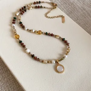 Detail of 18K gold plated beaded necklace with round pendant in bohemian style.