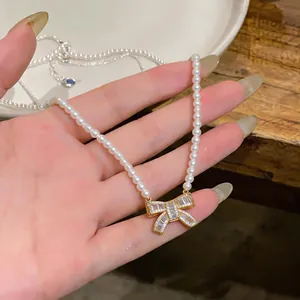Close-up of elegant bow pendant necklace with pearls and sparkling cubic zirconia stones.
