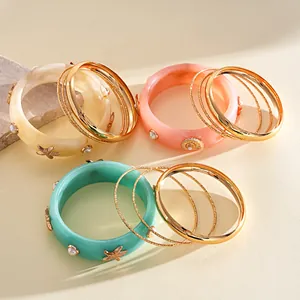 Close-up view of resort style resin and gold metal bangle set with starfish and faux pearls
