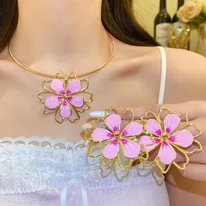 Detail of hollow-out gold flower jewelry set with pink enamel petals for elegant look
