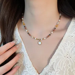 Close-up detail of bohemian style beaded necklace with stones and shell pendant on neck