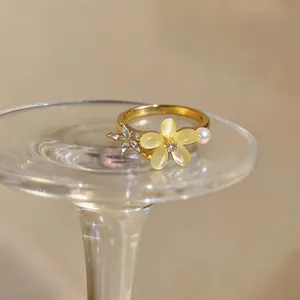 Macro detail of elegant gold-plated ring featuring zircon flower and pearl accent.