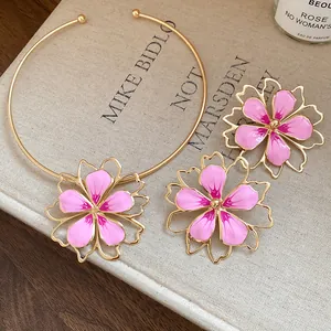 Close-up detail of elegant pink enamel flower choker and stud earrings set in gold.