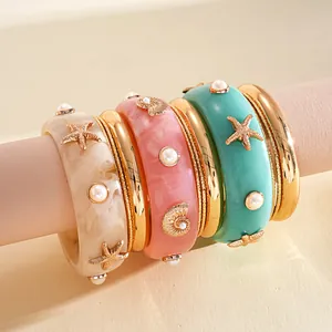 Detailed view of coastal style resin bangles with gold sea stars and pearls