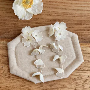 Close-up of handmade off-white mesh flower drop earrings showing delicate rhinestone centers