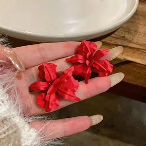 Detail shot showing the vibrant matte red finish and delicate petals of the flower earrings