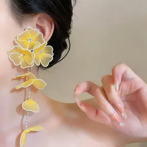 Detailed view of yellow hand-woven mesh flower long drop earrings worn by a model.