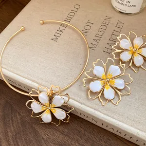 Detail of gold-toned choker and floral earrings with white and yellow enamel