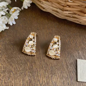 Close-up of 18k gold plated earrings with opal-like stones and sparkling zircons.