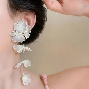 Close-up detail of white mesh flower drop earrings featuring elegant pearl accents