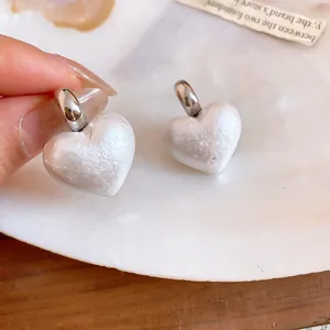 Primo piano di eleganti orecchini di perle bianche a forma di cuore con cerchi in argento