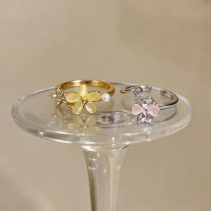 Elegant rotating flower rings with cat-eye stones and zircons on luxury glass stand.