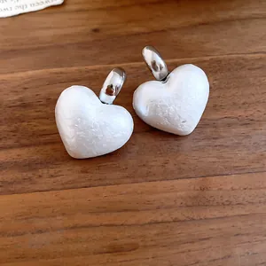 Primo piano di eleganti orecchini a perno con perle a cuore vintage francesi su legno.