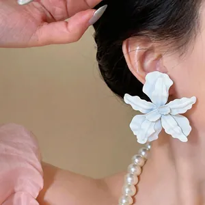 Detailed close-up showing white spray-painted flower earrings worn by an Asian model