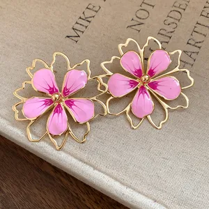 Detailed close-up showing pink enamel hollow flower stud earrings with elegant gold plating.